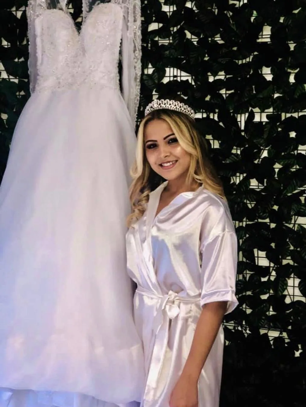 Noiva com coroa ao lado do vestido